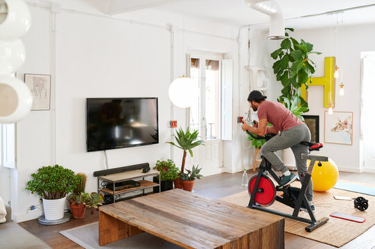 Fit Man Riding An Exercise Bike At Home