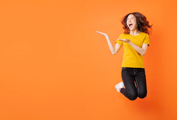 Young asian girl jumping up on orange background