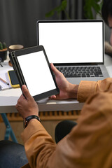 Cropped shot of businessman sitting in front of laptop computer and holding digital tablet.