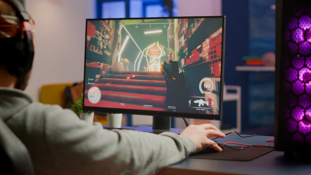 Gamer man with professional headphones relaxing in gaming room playing shooter video game on powerful computer. Virtual championship in cyberspace, esports player performing in gaming tournament