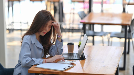 Young female accountant using calculator for calculate financial report and working with computer tablet at office.