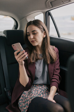 Young Woman Typing A Message on Phone In The Car