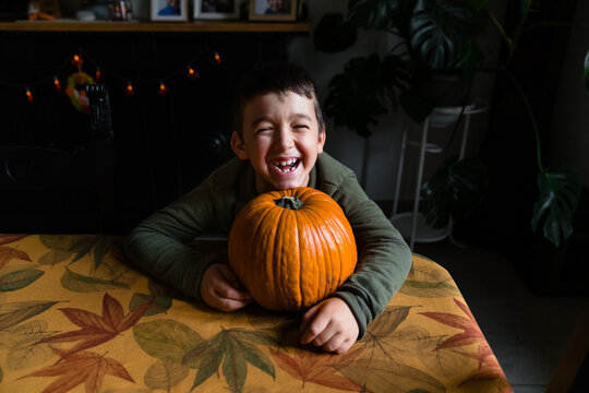 Laughing child with a pumpkin on a table