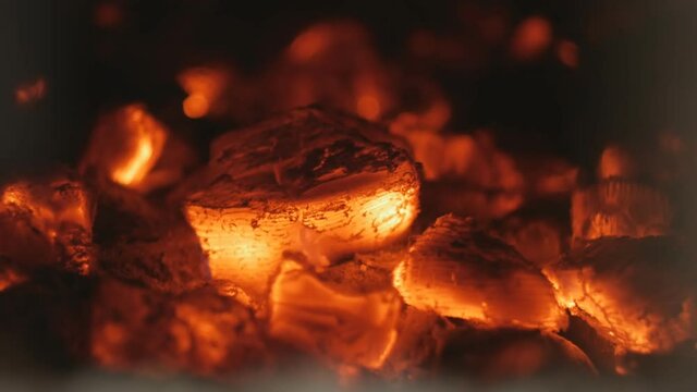 red coals in a fireplace or stove glow with bright lights. Close-up. The fire burned out, only coal and ashes died