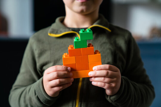 Child with pumpkin made of colored block toys
