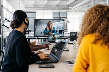 Multiehtnic group wearing face masks having a business virtual meeting