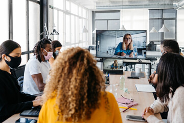 Multiehtnic group wearing face masks having a business virtual meeting