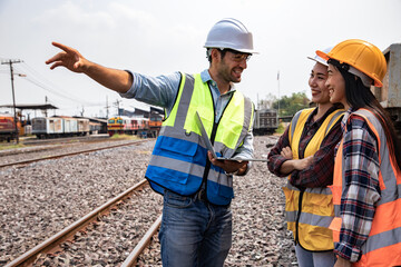 Engineers working on railway train statation and holding laptop for plan and meeting. Portrait of professional leadership of engineering teamwork. Warehouse and successful concept. 