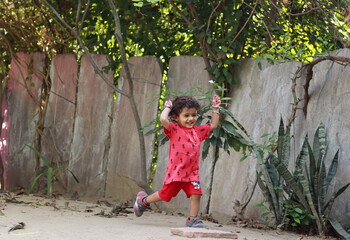 A small Hindu child resident in India playing a game of running in the courtyard of the house