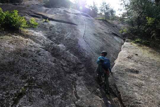 Rock climber looks up a granite cliff face.