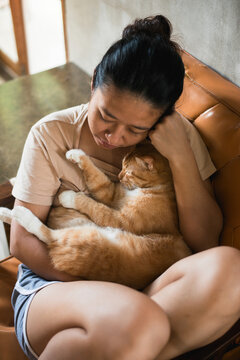 Asian woman hugging orange cat