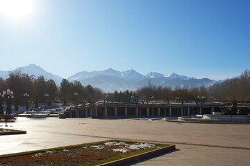 Fototapeta premium Beautiful mountains, green grass, snow, trees, blue sky. Spring. Park named after the first president, Almaty. Kazakhstan.