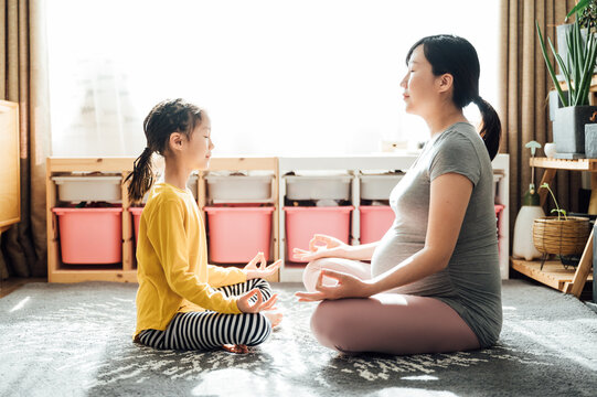 Pregnant mother and daughter doing yoga