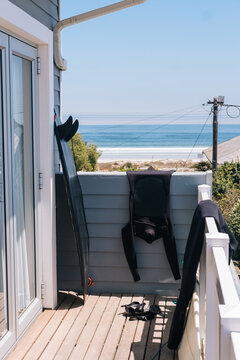 Surfboards and wetsuits drying on a balcony of a house with sea view