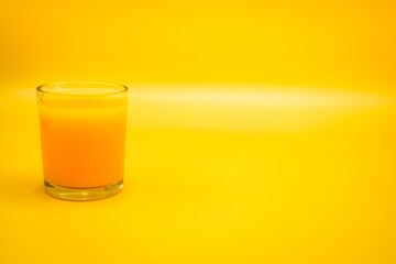 The glass of fresh orange juice on orange color background. The cup of a pure citrus cocktail is organic. Cold beverage for healthy in the tropical summer. Natural food drink squeezed pulp. Copy space