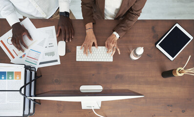 Crop coworkers at counter with papers and computer