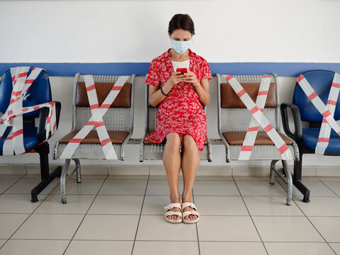 Woman sitting on seats crossed with caution tape in times of pandemic