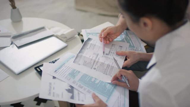 Middle-aged caucasian woman using services of financial consultant from home managing budget and analyzing statements together