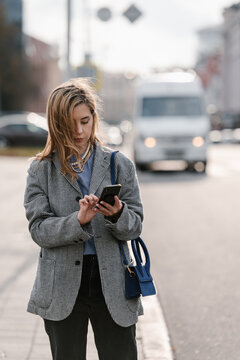 Serious woman browsing mobile phone on street