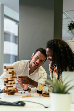 Cheerful colleagues playing Jenga game at workplace