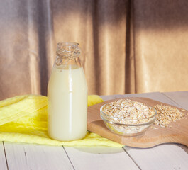 Glass bottle with vegetable oat milk and oat flakes. Lactose-free milk, vegetarianism.