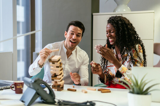 Cheerful colleagues playing Jenga game at workplace