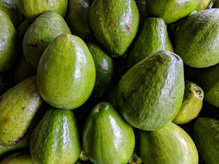 A close-up photo from above of a bunch of avocados on display at a roadside fruit shop with selective focus