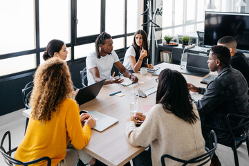 Group of multiracial businesspeople sitting around table having a meeting in modern workplace