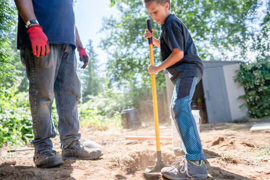 Boy uses tamper to pack dirt