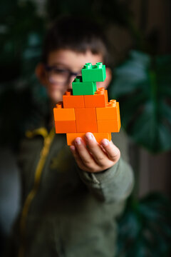 Child showing a pumpkin made of colored block toys