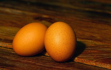Two brown chicken eggs on the old teak table, in shallow focus