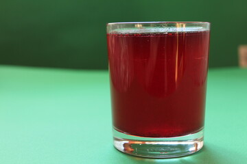 Red drink juice or compote in a glass on a green background with a place for text and copyspace
