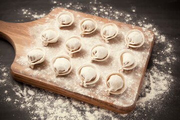 semi-finished pelmeni dumplings on the wooden board.