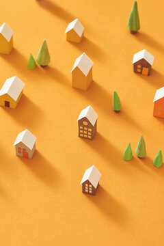 Handmade small houses with pine trees on a yellow background