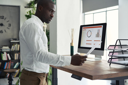 Elegant black male checking document working at table in office