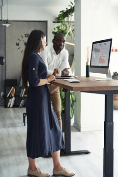 Modern diverse colleagues at counter table with desktop