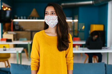 Modern woman in protective mask standing in coworking room