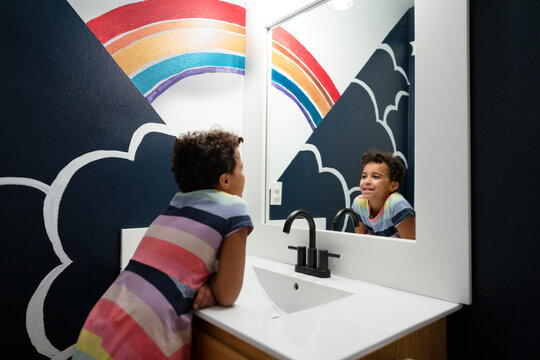 Girl reflected in mirror with rainbow mural