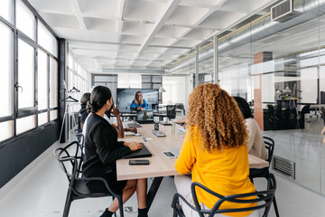 Group of multiracial businesspeople sitting around table having a remote video conference in modern workplace
