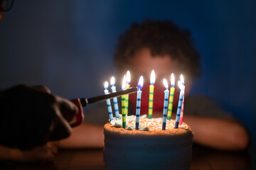 Hand lights candles on birthday cake