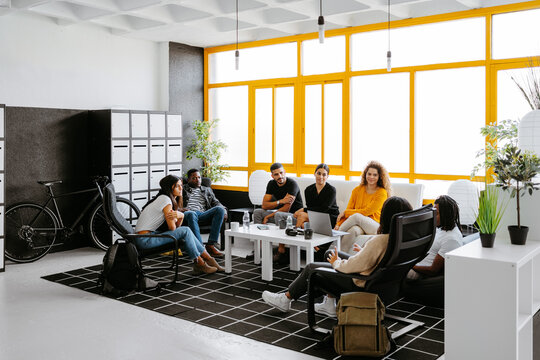 Group of diverse coworkers having a relaxed conversation during coffee break in a modern work place
