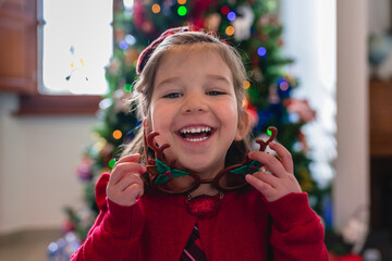 Playful Little Girl in front of a Christmas Tree