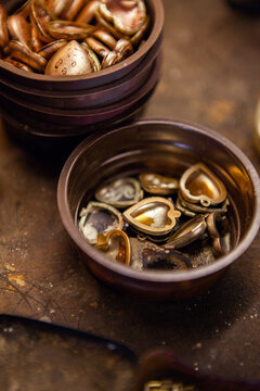 A bowl of pendant locket metal pieces ready to be assembled.