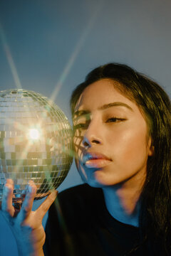 A model with dark hair holding a disco ball