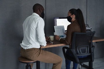 Serious business partners in masks meeting in office