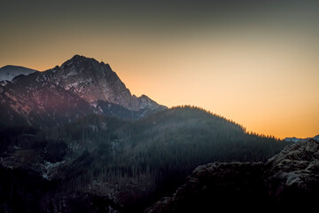 The sun is setting behind Giewont Peak - a legendary peak in Tatra Mountains, Poland. Selective focus on the rocky ridge, blurred background.