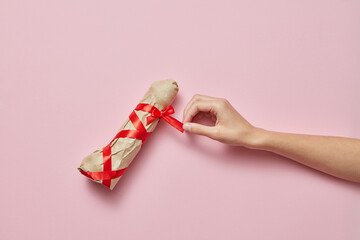 Woman's hand with sex gift vibrator wrapped of paper.