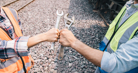 Knuckle bump hands of Engineers group working on train garage site and holding old wrench for...