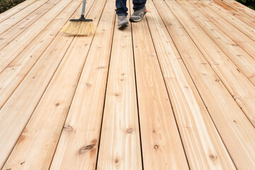 Feet of child sweeping cedar deck