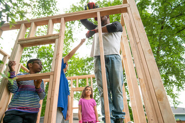 Boy hands screw to his father as they build playhouse